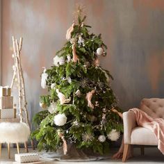 a decorated christmas tree in a living room next to a pink chair and white rug