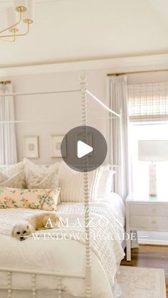 a white bed sitting in the middle of a bedroom next to a window with curtains