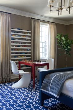 a bed room with a neatly made bed next to a table and chairs in front of a window