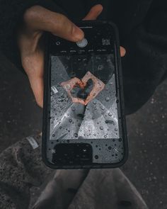 a person holding an iphone in their hand with water droplets on the screen and heart drawn on it