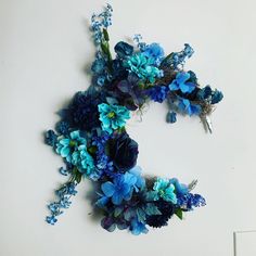 blue flowers are arranged in the shape of the letter c on a white wall,