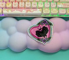 a pink heart shaped pillow sitting next to a keyboard