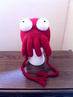 a red knitted hat with two eyes on top of a table