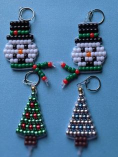 three beaded christmas tree ornaments on a blue surface with one being a snowman and the other is a penguin