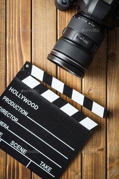 a movie clapper next to a camera on a wooden background - stock photo - images