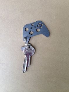 a video game controller shaped keychain with two keys attached to it, sitting on a table