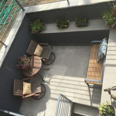 an overhead view of a patio with tables and chairs on the ground, surrounded by potted plants