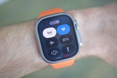 an orange apple watch on someone's wrist with the screen showing different buttons and symbols