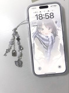 a cell phone with an anime character on it next to some charms and a keychain