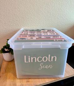 a plastic box filled with pink and white tickets sitting on top of a wooden table