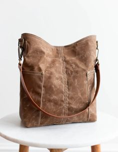 a brown leather bag sitting on top of a white table next to a wooden stool