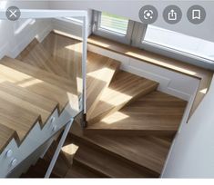 an overhead view of a wooden staircase with white handrails and wood flooring