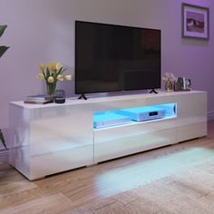 a living room with purple walls and a flat screen tv on top of a white entertainment center