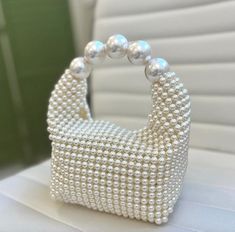 a white purse with pearls on it sitting on top of a table next to a window