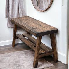 a wooden bench sitting in front of a mirror next to a rug on the floor