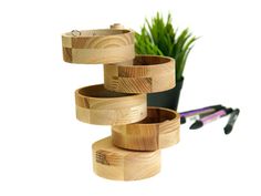 three wooden containers stacked on top of each other next to a potted green plant