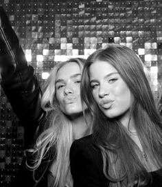 two beautiful young women standing next to each other in front of a disco ball wall