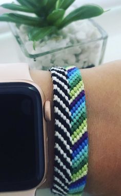 an apple watch on someone's wrist with a colorful bracelet attached to the band