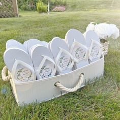 white flip flops are arranged in a basket on the grass with flowers behind them