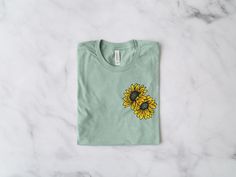 Sunflower T-Shirt *Product Details - Unisex T-Shirt - Ultra soft Bella Canvas 3001 - Designed with high quality pre-shrunk combed and ring-spun cotton - Features a crew neck with shoulder to shoulder taping and side seams *Sizing and Colors - Please refer to sizing and color charts in the images *Fabrication - Solid colors: 100% combed and ring-spun cotton - Heather colors: 52% combed and ring-spun cotton, 48% polyester - Athletic Heather colors: 90% combed and ring-spun cotton, 10% polyester - Casual Green Sunflower Print Top, Crew Neck Cotton T-shirt With Sunflower Design, Green Cotton Sunflower Print Top, Green Cotton Top With Sunflower Print, Spring Green T-shirt With Custom Print, Cotton T-shirt With Sunflower Design, Green Custom Print T-shirt For Spring, Cotton Crew Neck Top With Sunflower Design, Cotton Top With Sunflower Design And Crew Neck