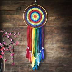 a colorful dream catcher hanging on a wooden wall next to a vase with pink flowers