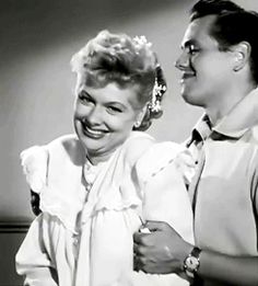 an old black and white photo of two women laughing together, one is wearing a dress