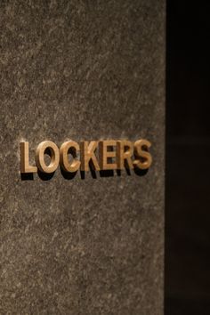 the word lockers written in gold on a granite wall