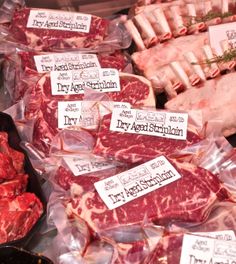 various meats are on display for sale at a butcher's shop with price tags attached to them