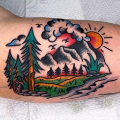 a tattoo with mountains and trees on it