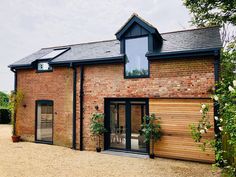 a brick building with a wooden door and windows on the outside, surrounded by greenery