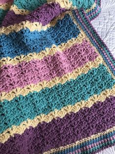 a crocheted blanket is laying on top of a quilted tablecloth,