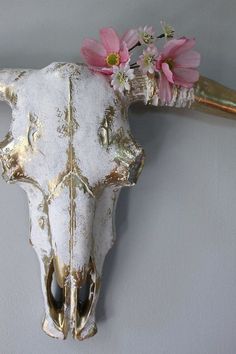 a cow's skull with pink flowers on it is mounted to the wall in front of a gray wall