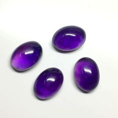 three purple stones sitting on top of a white table