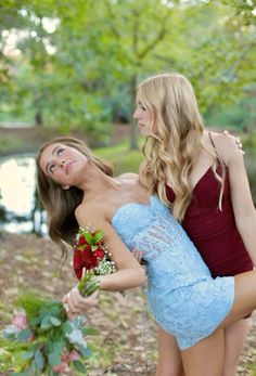 two beautiful young women standing next to each other holding bouquets in their hands and looking at each other