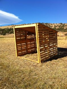 a wooden outhouse sitting on top of a dry grass field