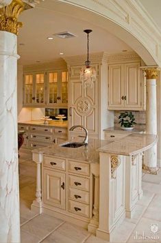 a large kitchen with marble counter tops and white cabinets, along with an archway leading to the dining room