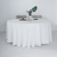 a white table with two chairs and a plant in a vase on the table top