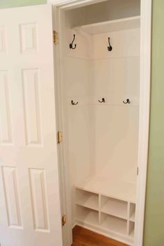 an empty white closet with several hooks on the door