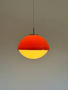 a red and yellow light hanging from a ceiling in a room with grey walls,