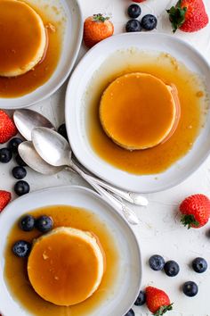 three white plates topped with pancakes and blueberries on top of a table next to strawberries