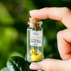 a person holding a tiny bottle with a rubber duck in it