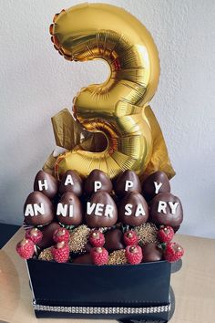 a birthday cake with chocolate covered strawberries and balloons in the shape of number three