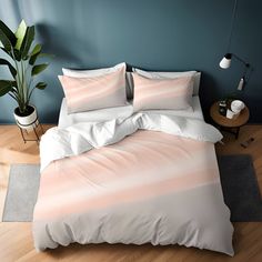 a bed with two pillows on top of it next to a potted plant and lamp