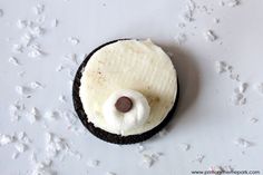 an oreo cookie topped with white frosting and a brown teddy bear's nose