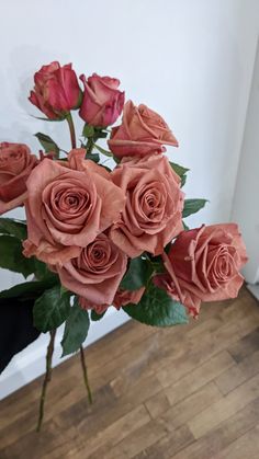 a vase filled with pink roses on top of a wooden floor