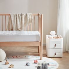 a baby's bed with toys on the floor and a dresser in the background