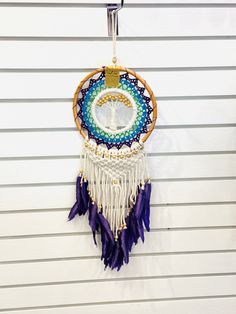 a colorful dream catcher hanging on the side of a building with white siding and blue trim