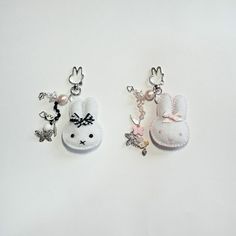 two keychains with charms attached to them on a white surface, one has a bunny and the other is a rabbit