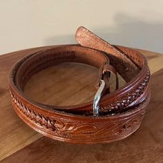 Decorative brown leather belt with hand-tooled details and a simple silver metal buckle. The belt measures 42" and is a marked size 34, made in Mexico. There are 5 belt holes and there is light wear on the inside of the belt near the belt holes. Belts Aesthetic, Thrift Inspo, Brown Leather Belt, Suspender Belt, Phoenix Az, Vintage Brown, Metal Buckles, Leather Belt, Phoenix