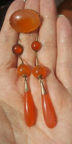 The colours of these carneliuns are so dreamy, they are not garish but a soft orange. The earrings are 2 3/4 inches long from the top of the ear wire to the bottom drop. As you can see from the pictures, the tops are slightly different but when worn you cannot tell. These were mine and I wore them for years like this.  The drops are tested to gold of 14k and so is the brooch. The sweet brooch is almost 1 inch wide and 11/16 inch tall. This is a lovely, lovely set. C. 1840 and English. Follow me on instagram@jettesjewels. Orange Carnelian Dangle Earrings, Orange Carnelian Gemstone Earrings, Orange Gemstone Dangle Earrings, Vintage Orange Jewelry With Matching Earrings, Vintage Orange Round Earrings, Orange Clip-on Earrings For Formal Occasions, Orange Teardrop Jewelry For Formal Occasions, Formal Orange Clip-on Earrings, Orange Gemstone Drop Earrings